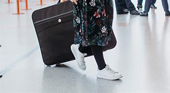 Photo of women wheeling suitcase in airport departures