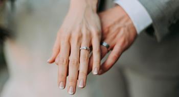 Photo of hands holding with wedding rings on