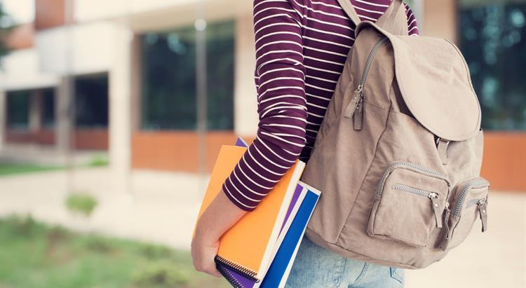 Student wearing a backpack and carrying books