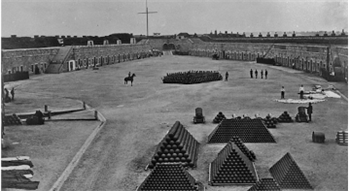 Historical black and white image of Fort Regent parade ground with stacks on cannon balls