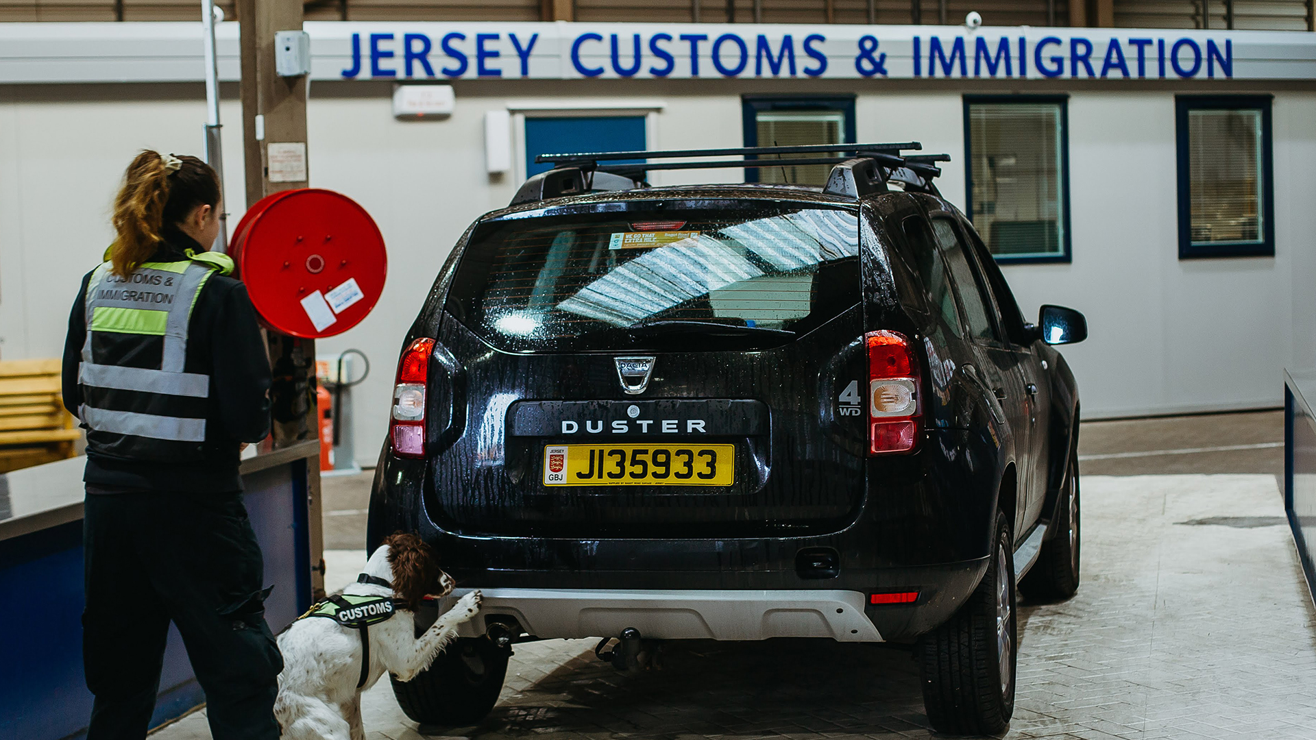 Photo of vehicle being checked by customs officer and dog