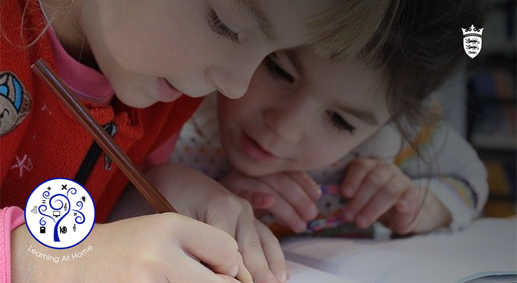 Two children lean over a piece of paper 