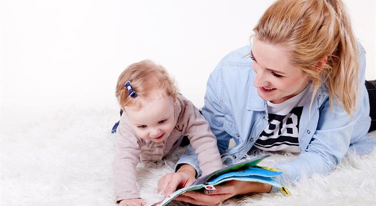 Nursery assistant reading book with baby