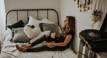 Woman sitting on bed with cup of tea