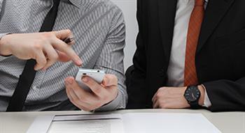 Photo of colleagues working and pointing to a phone