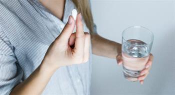 woman about to take tablet with water