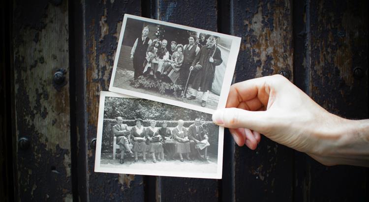a hand holds up two old family photographs