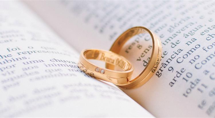 Photo of gold wedding ring placed on open book